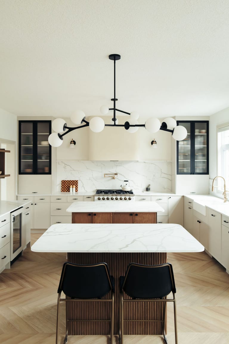 Black counter stools at a kitchen island with a fluted wood base, under a black globe chandelier.
