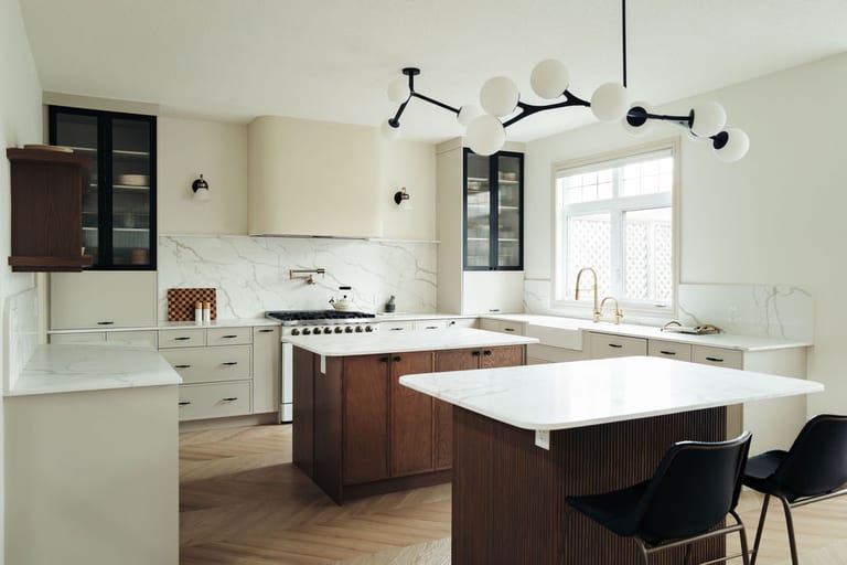 Renovated kitchen with a walnut island, white cabinets, marble backsplash and globe pendant lights.